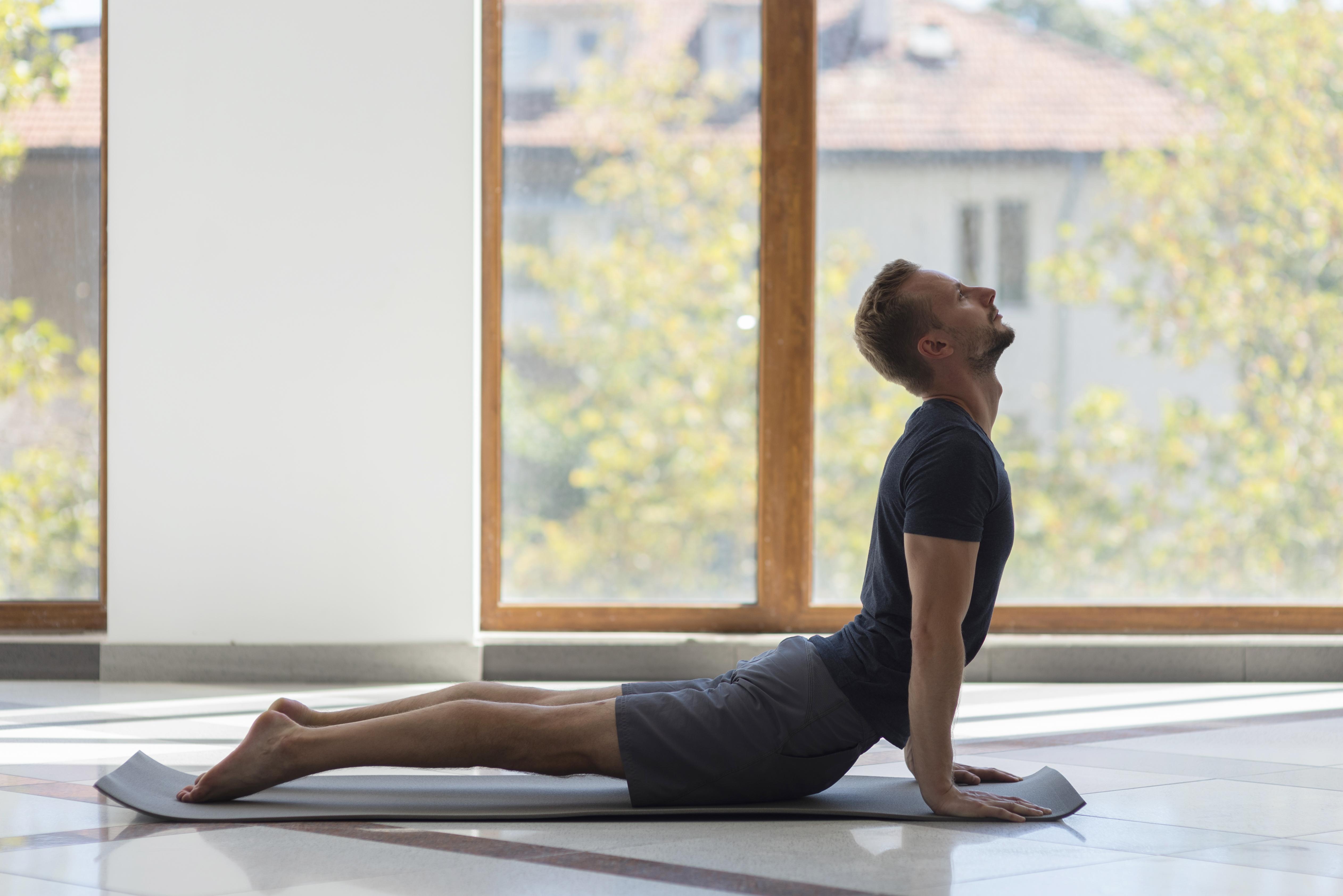 full-shot-man-practicing-cobra-pose-indoor